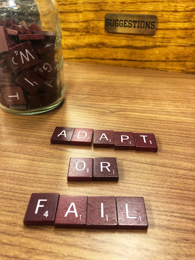 Tiles from a board game spell out the words adapt or fail.